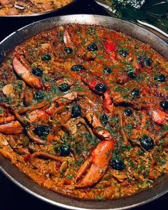 Arroz con bogavante y aceitunas negras en paella