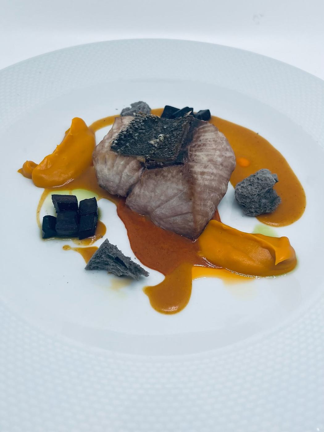 Pescado con salsa de calabaza y crujientes negros