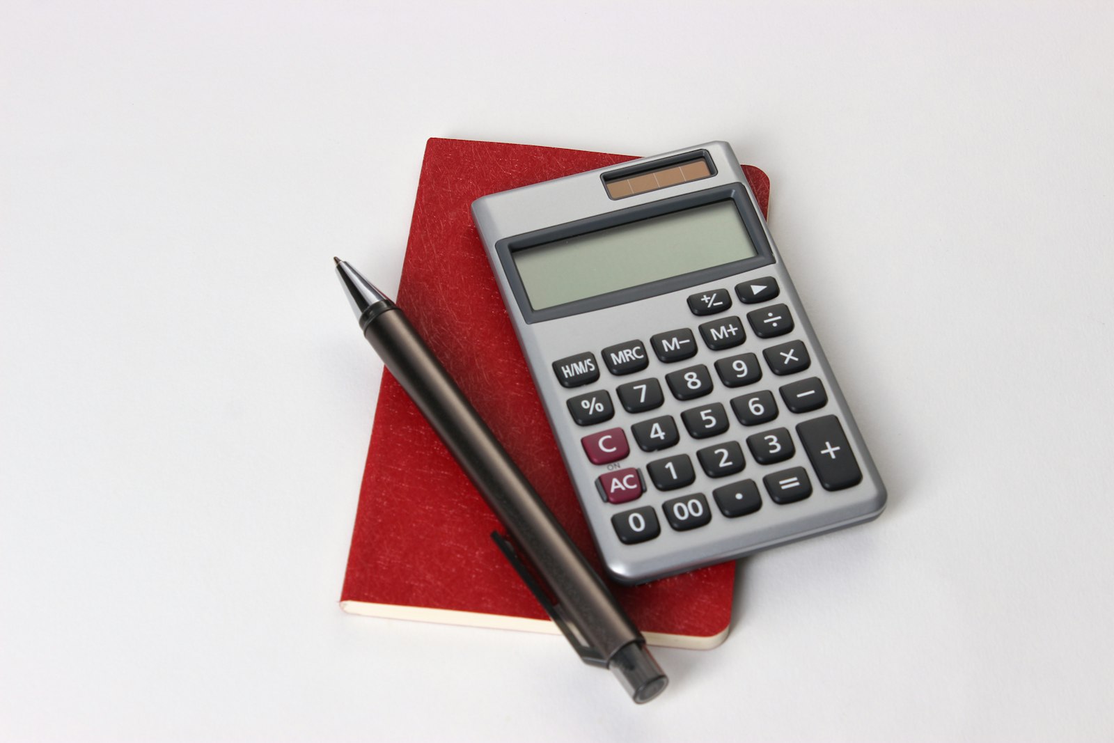 Calculadora y bolígrafo sobre un cuaderno rojo, con cálculos de coste